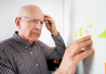 Dementia. Vanhempi mies tutkii muistilappua jääkaapin ovesta.